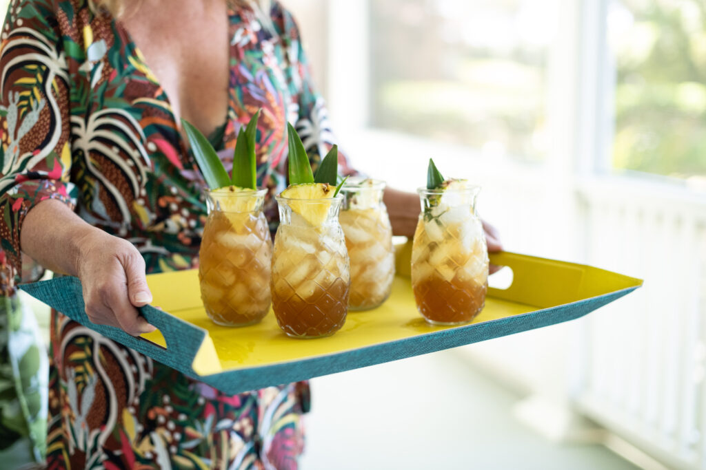 Hand serving sweet tea spritzers on a bright tray — a refreshing porch idea for REALTORS® hosting clients with genuine Southern hospitality.